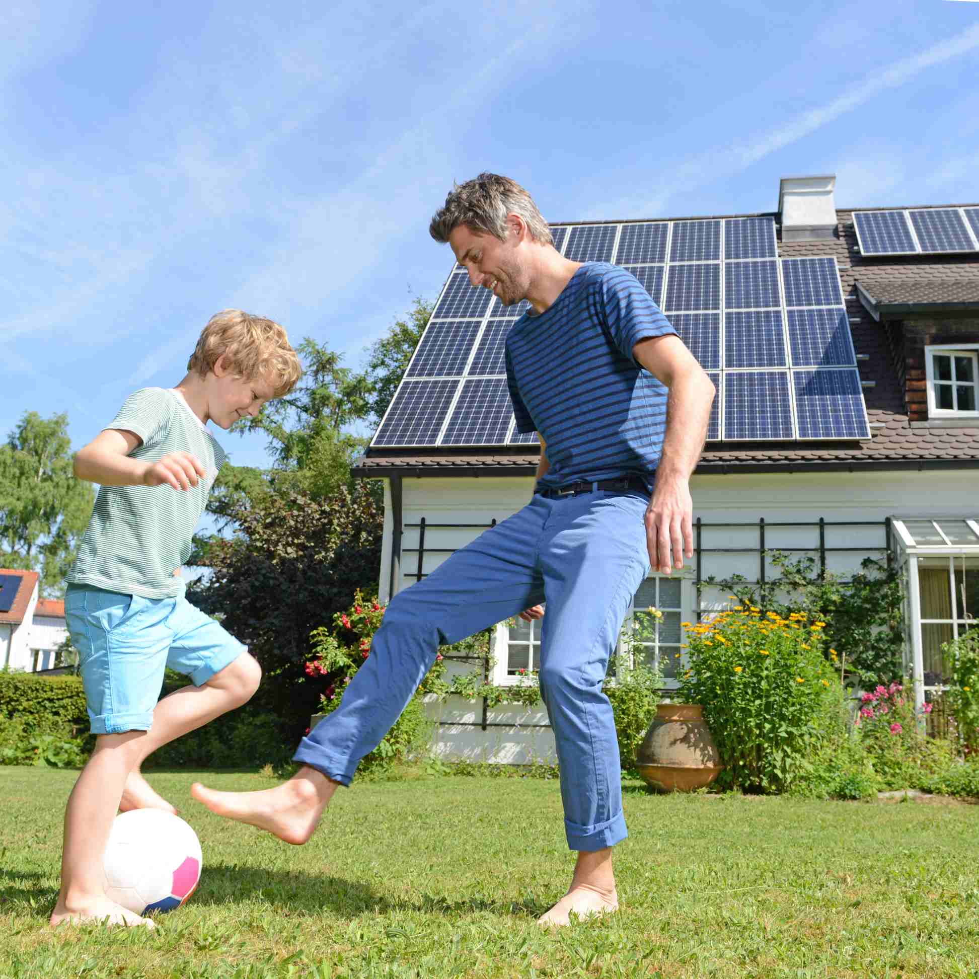 Father and son playing football in garden of solar paneled house virginia beach va
